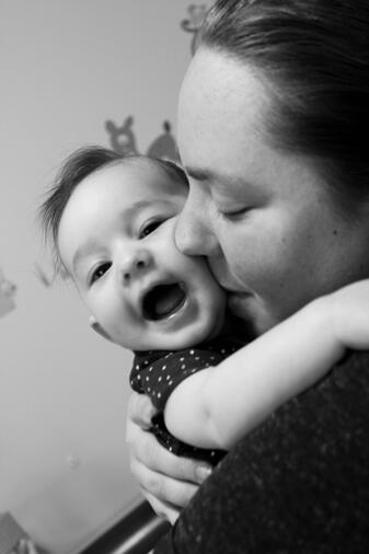 A woman kissing her infant on the cheek. Infant looks happy!